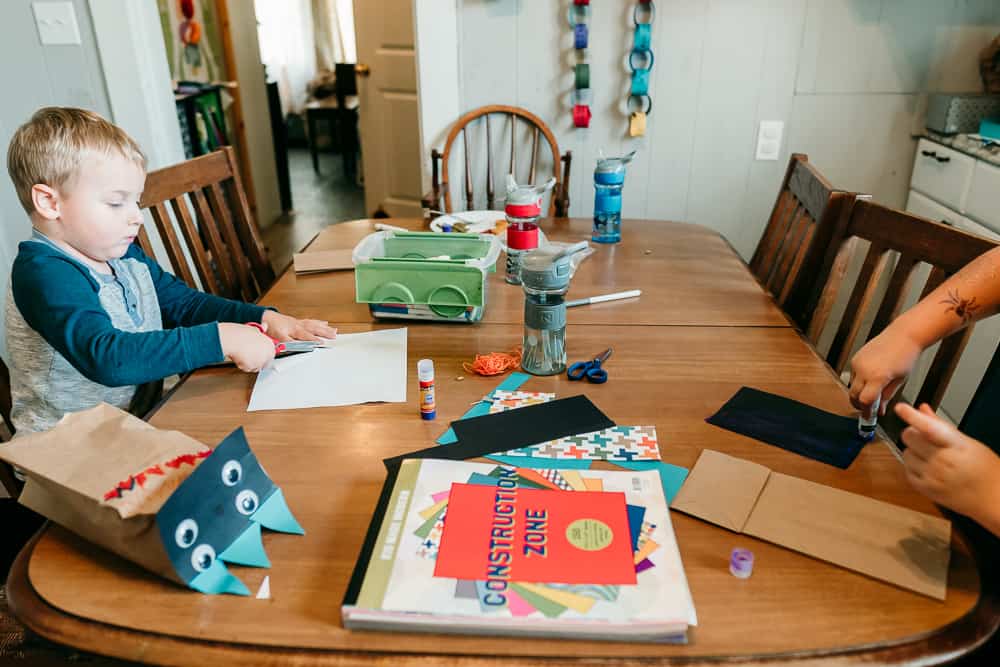 Boy cutting paper to make paper bag monster puppet