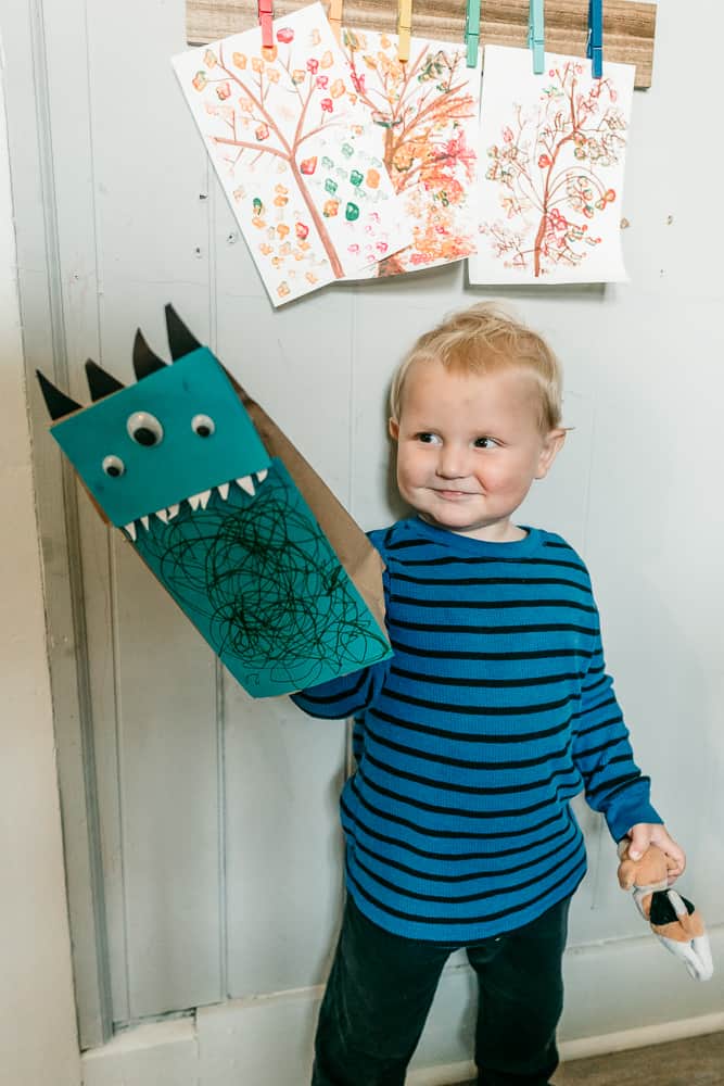 Little boy playing with paper bag monster puppet