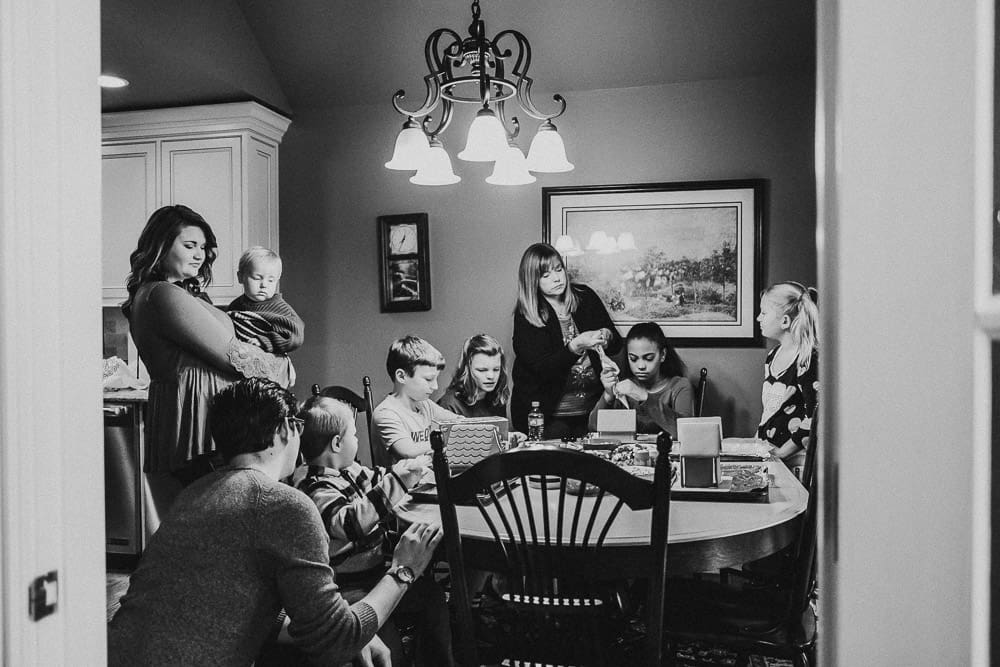 Gingerbread house decorating party - extended family sitting around a table in the kitchen decorating gingerbread houses