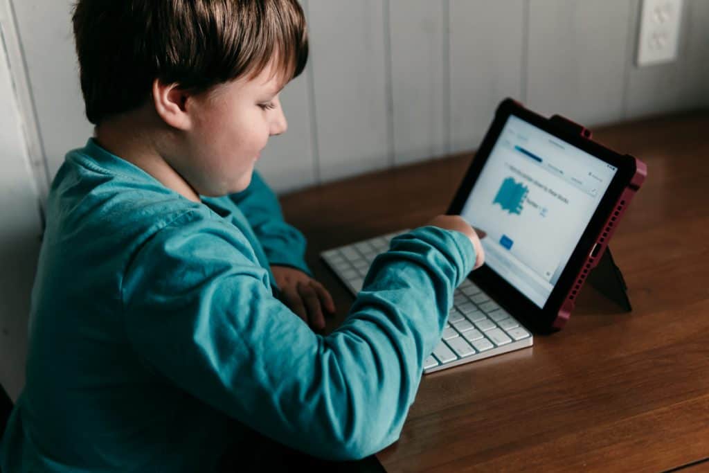 Boy sitting at a table with an iPad doing his online math curriculum