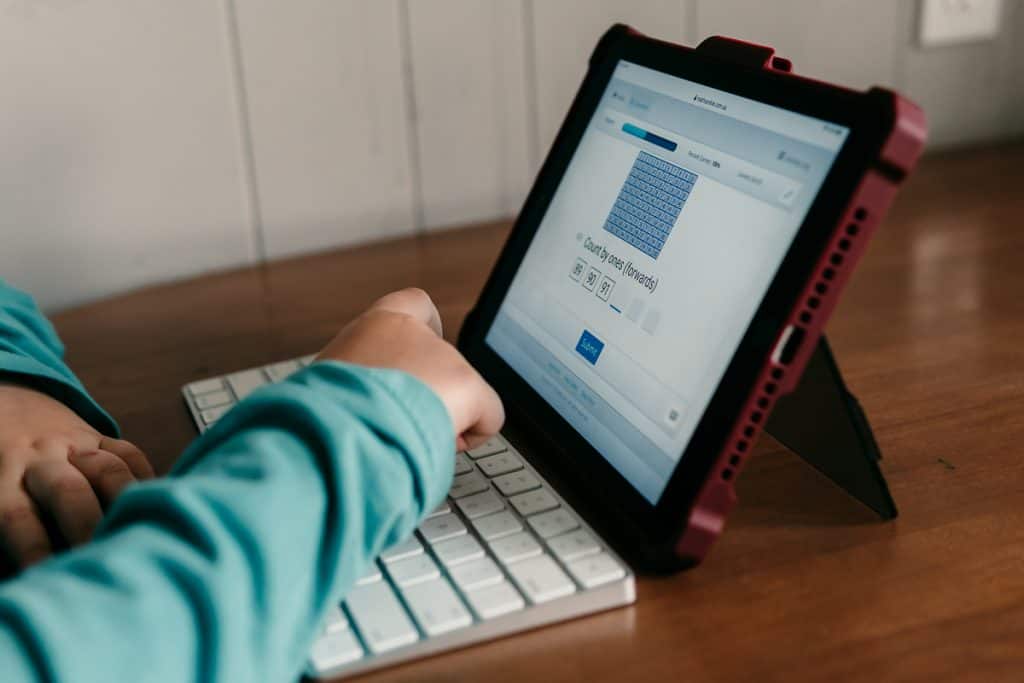 iPad sitting on table with hand typing in answers on CTCMath lesson