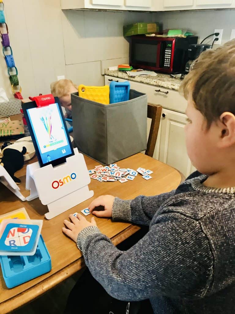 Boy playing Osmo numbers game with hands-on number pieces.