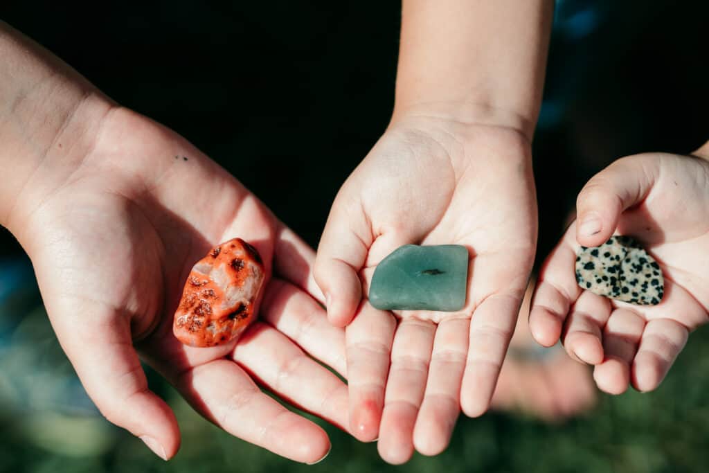 three hands holding rocks in their palms